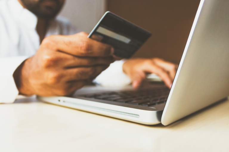 A man making a purchase on his computer with a credit card.